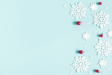 Christmas or winter composition. Frame made of snowflakes and red berries on pastel blue background. Christmas, winter, new year concept. Flat lay, top view, copy spaceの写真素材