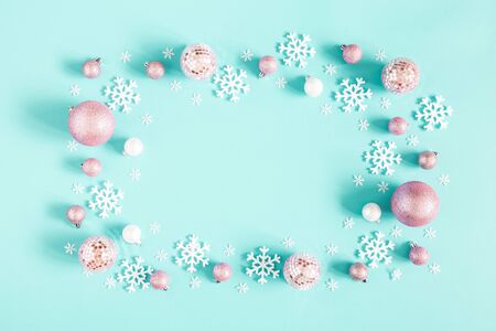 Christmas composition. Frame made of pink balls and white snowflakes on pastel blue background. Christmas, winter, new year concept. Flat lay, top view, copy spaceの写真素材