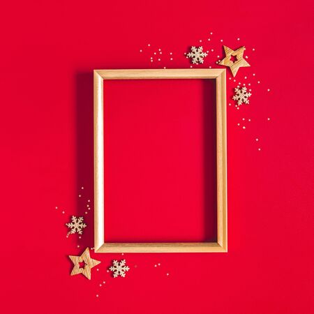 Christmas composition. Photo frame, golden and red decorations on red background. Christmas, winter, new year concept. Flat lay, top view, copy spaceの写真素材