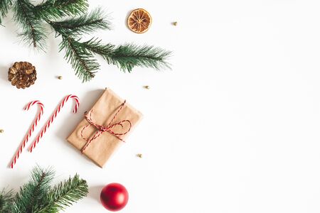 Christmas composition. Fir tree branches, red balls, gift box on white background. Christmas, winter, new year concept. Flat lay, top view, copy spaceの写真素材