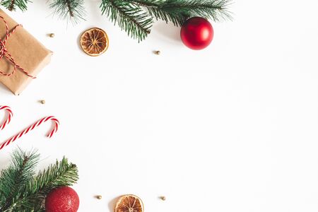 Christmas composition. Fir tree branches, red balls, gift box on white background. Christmas, winter, new year concept. Flat lay, top view, copy spaceの写真素材