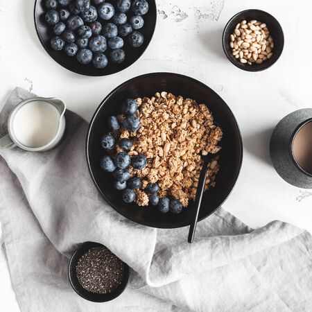 Breakfast with muesli, blueberry, coffee on white background. Healthy food concept. Flat lay, top viewの写真素材