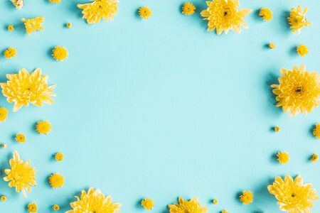 Flowers composition. Frame made of yellow chrysanthemum flowers on blue background. Flat lay, top viewの写真素材