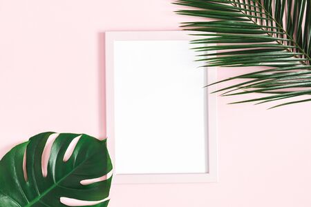 Summer composition. Tropical leaves, photo frame on pink background. Summer concept. Flat lay, top view, copy spaceの写真素材