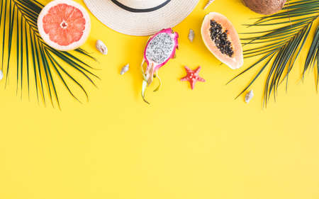 Summer composition. Tropical palm leaves, hat, pineapple, coconut, sea shells on yellow background....