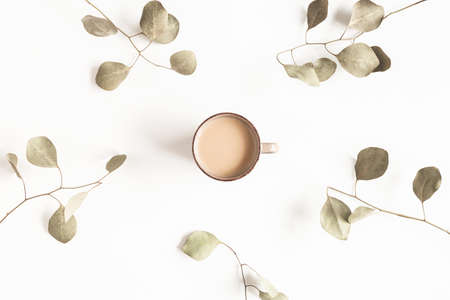 Autumn composition. Cup of coffee, eucalyptus leaves on white background. Autumn, fall, winter concept. Flat lay, top viewの写真素材
