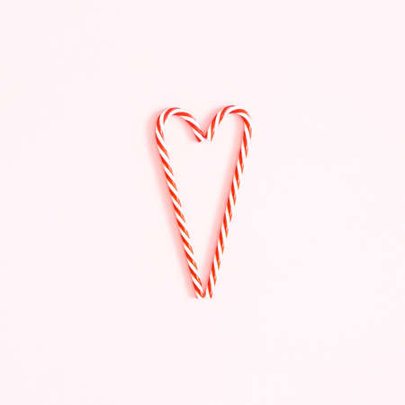 Christmas composition. Heart made of candy canes on pink background. Christmas concept. Flat lay,...