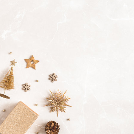 Christmas composition. Golden decorations on marble beige background. Christmas, winter, new year concept. Flat lay, top view, copy spaceの写真素材