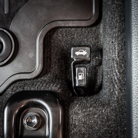 Close up hand switch of car fuel tank and hood. Car interior