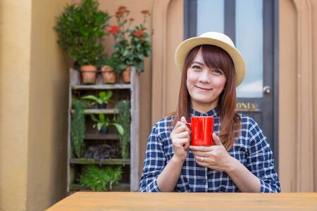 wear hat woman sitting in outdoor with warm drink relaxの写真素材