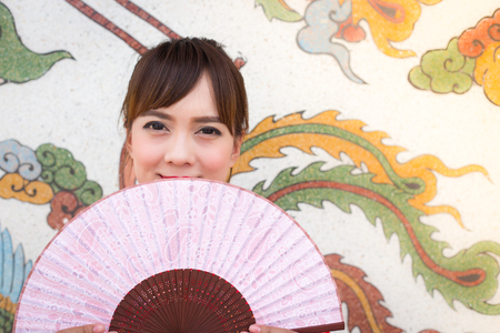 Beautiful Asian woman wearing traditional Cheongsam on chinese pattern traditional backgroundの写真素材