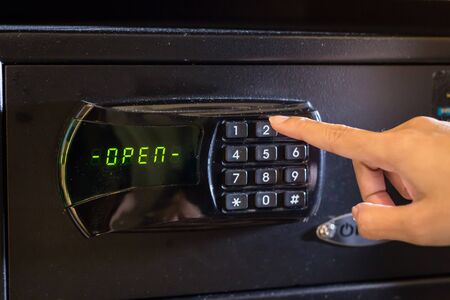 Hand press key on black safety box with open statusの写真素材