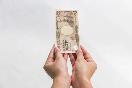 Businesswoman giving money and holding 10,000 japanese yen money in hand Isolated on white...