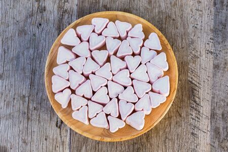 White heart Fluffy white Marshmallow heart in a wooden dish on a wooden background. Copy space...