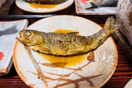 Iwana fish or Salvelinus grilled on a plate topped with Japanese sauce water on table and food set.の写真素材
