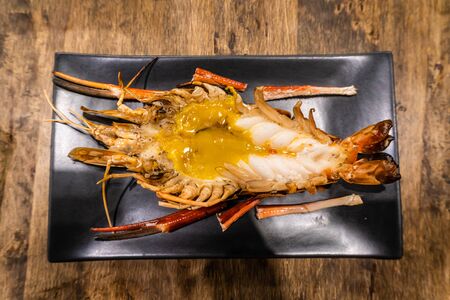 Fresh grilled river prawns with a lot of fat on the head resting on a plate. Is a famous food of Ayutthaya, Thailand.の写真素材