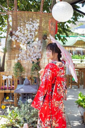The girl is wearing a red traditional kimono, which is the national dress of Japan and Hold an umbrellaの写真素材