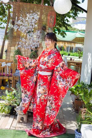 The girl is wearing a red traditional kimono, which is the national dress of Japanの写真素材