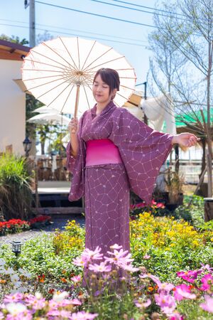 The girl is wearing a pink traditional yukata, which is the national dress of Japan and Hold an umbrellaの写真素材