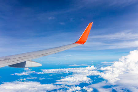 Airplane wings flying in the sky with cloudsの写真素材