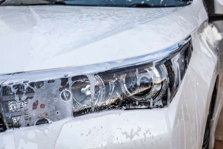 Lather from the car wash liquid on the modern headlights.の写真素材