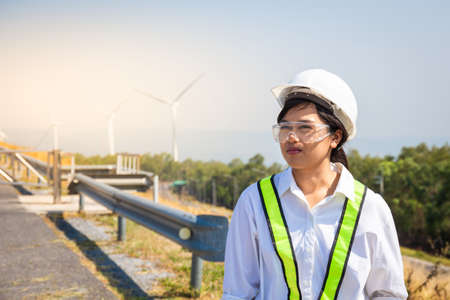 Asian women engineer stands confidently at outdoor on site power plant energy wind turbinesの写真素材