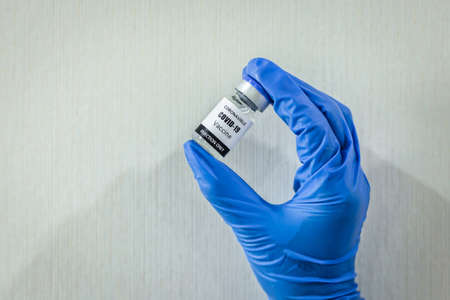 The coronavirus or COVID-19 vaccine is carried by a blue gloved medical professional.