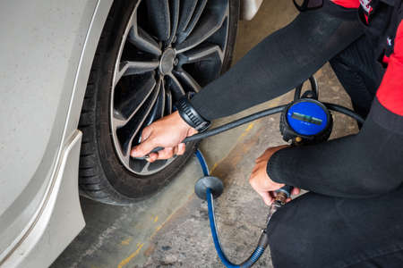 Expert mechanic checks tire pressure with nitrogen and has a pressure gauge.の写真素材