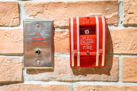 Fire alarm on a brick wall with an emergency telephone jack during fire.の写真素材