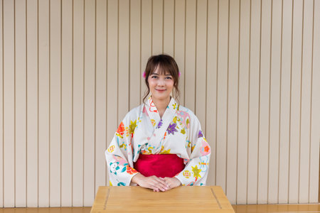 Young woman wearing Japanese traditional kimono in Japanese style house with wooden table.の写真素材