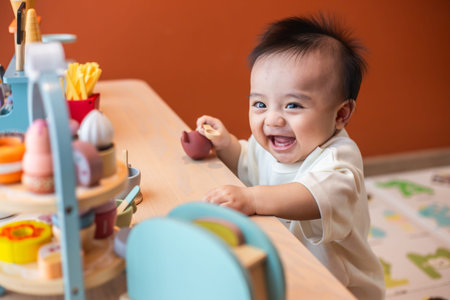 A cute little child smiles very happy while playing with toys made from wood and non-toxic paint to...