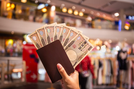 Japanese 10,000 yen banknote in hand and tourist passport used to buy and sell goods, traditional...