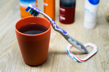 Oral cleanser for good oral health, glass of mouthwash on a table with toothbrush and toothpaste in foregroundの写真素材