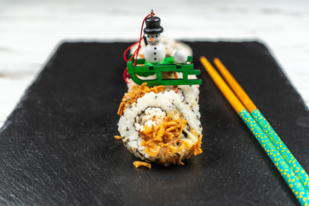 Group of fresh sushi with wooden chopsticks on a black stone plate board and on a white rusty background.Soft focus shot.の写真素材