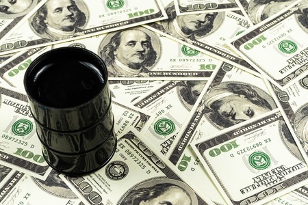 Spilled oil from a barrel to a dollar bill background.Oil barrel price concept.の写真素材