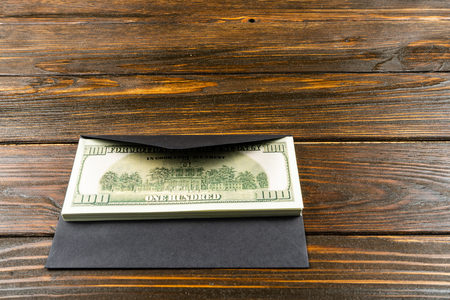Prop Money Dollars in black envelope.Brown wooden backgroundの写真素材