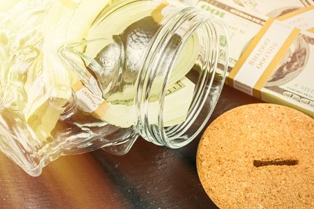 Large Piggy Bank Money Box,Glass Money Jar with bricks of 100 US dollars,sunbeam effect.の写真素材