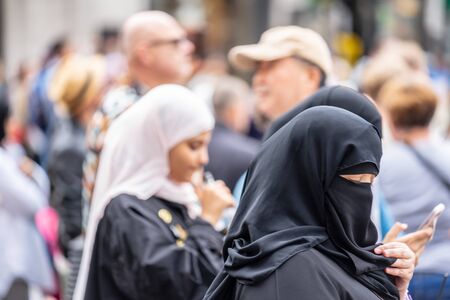 London, UK, July, 2019. A Muslim woman in London wearing a niqab, using mobile phone while shopping. Selected focusのeditorial素材