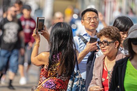 Cambridge, UK, August 1, 2019. Turists walking down and taking pictures at the street of Cambridge on a busy sunny day in front of Kings Collegeのeditorial素材