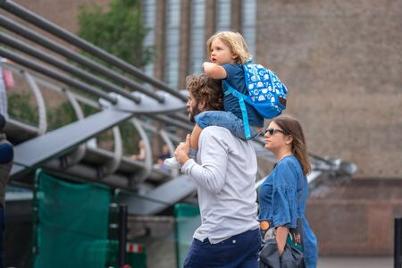 London, UK, July, 2019. Little boy sitting on father's shoulders near Millennium Bridge over the River Thames in London.のeditorial素材