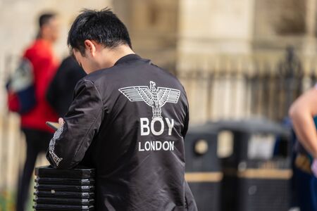 Close up handsome young man using smart phone while standing outdoors at sunny evening, rear view shot hipster man holding cell phoneのeditorial素材