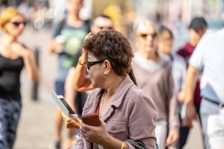 Cambridge, UK, August 1, 2019. Rear view of a woman takes photos using smart mobile cell phone camera.Soft focusのeditorial素材