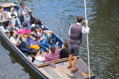 Cambridge, UK, August 1, 2019. The punter pushes a pole against the river bed and this gives the punt a way to moveのeditorial素材