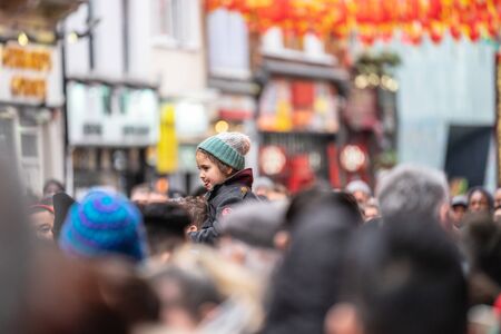 London, January 26, 2020. A smiling young girl sitting on her fathers shoulders whilst walking through a crowd at Chinatown. New Year Celebrationsのeditorial素材