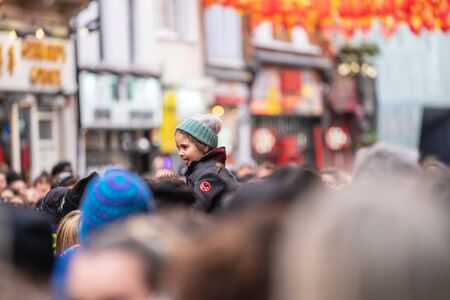 London, January 26, 2020. A smiling young girl sitting on her fathers shoulders whilst walking through a crowd at Chinatown. New Year Celebrationsのeditorial素材