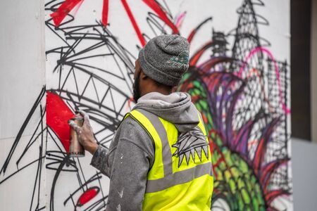 London, January 26, 2020. Professional painter at work, painting a street wall.Young man painting...