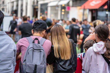 London, UK, July 14, 2019. Young couple at busy London street watching street performance. View from behind.のeditorial素材