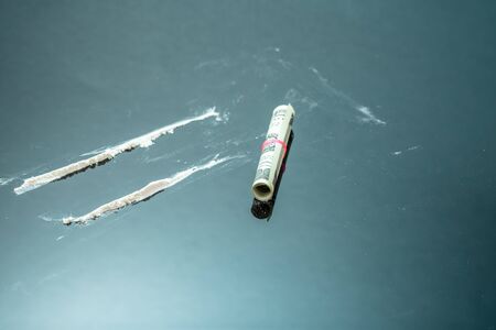 Cocaine powder in lines and a dollar bill. Narcotic stripes on black background