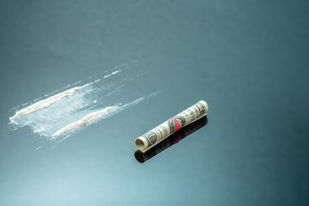 Cocaine powder in lines and a dollar bill. Narcotic stripes on black backgroundの写真素材