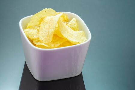Potato chips, or crisps on black mirror background